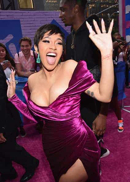 Cardi B waves wearing purple gown