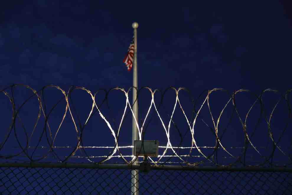 American Flag flying over prisob barbed wire fence at twilight