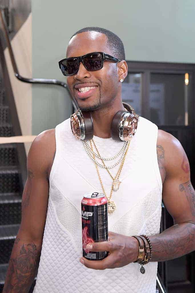 Safaree drinking amp energy drink with gold headphones around neck