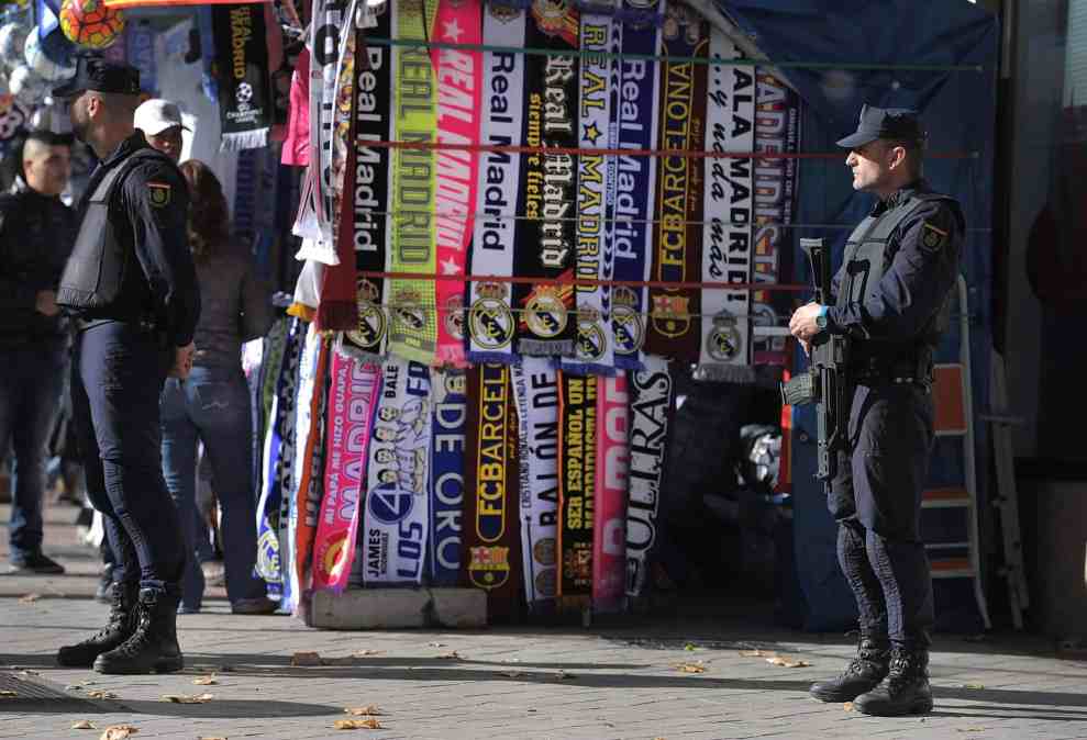 Police stand in front of stand selling Real Madrid soccer scarfs