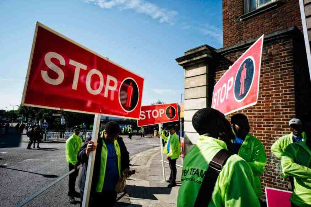 Protesters holding signs reading "Stop"