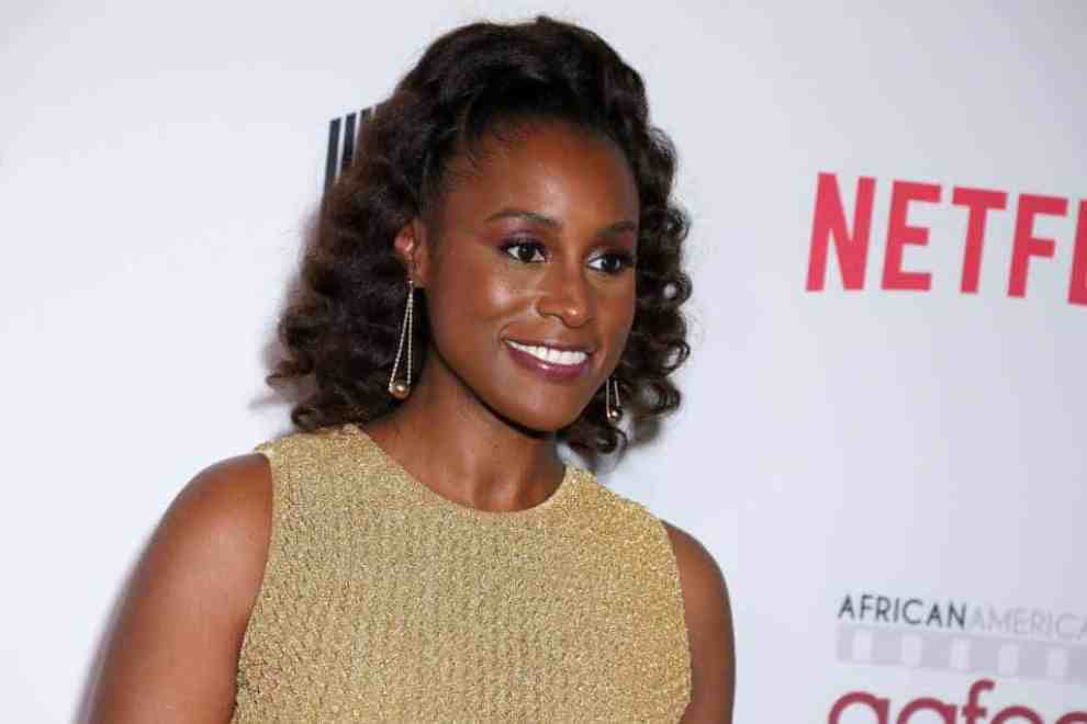 Issa Rae smiling wearing a gold dress