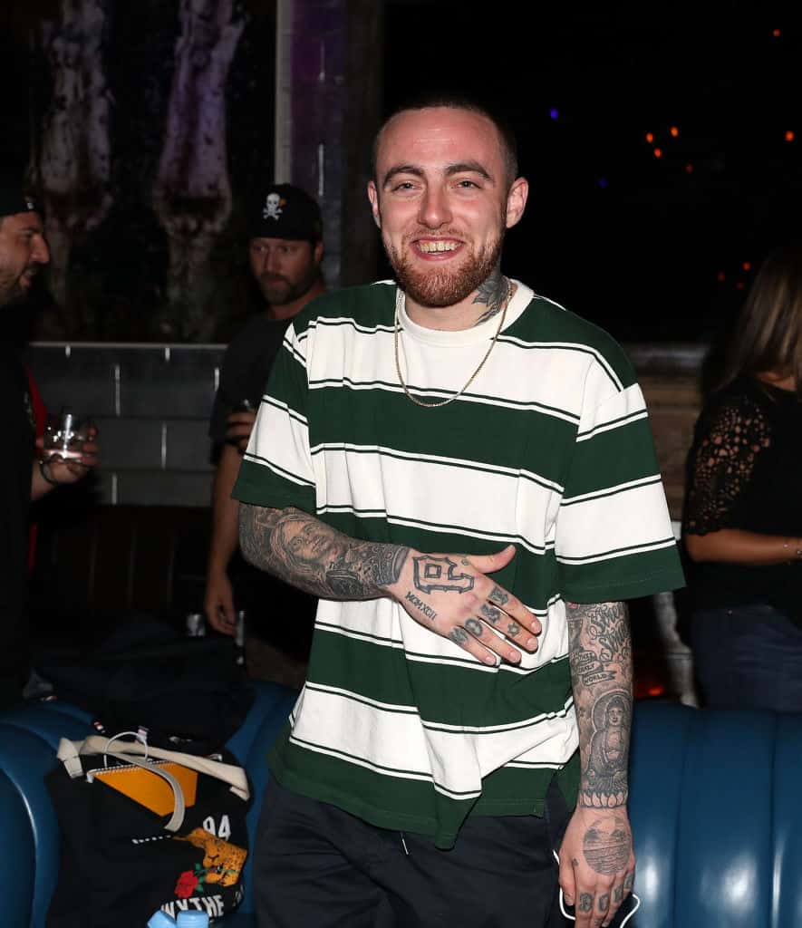Mac Miller smiling wearing a green and white stripe shirt