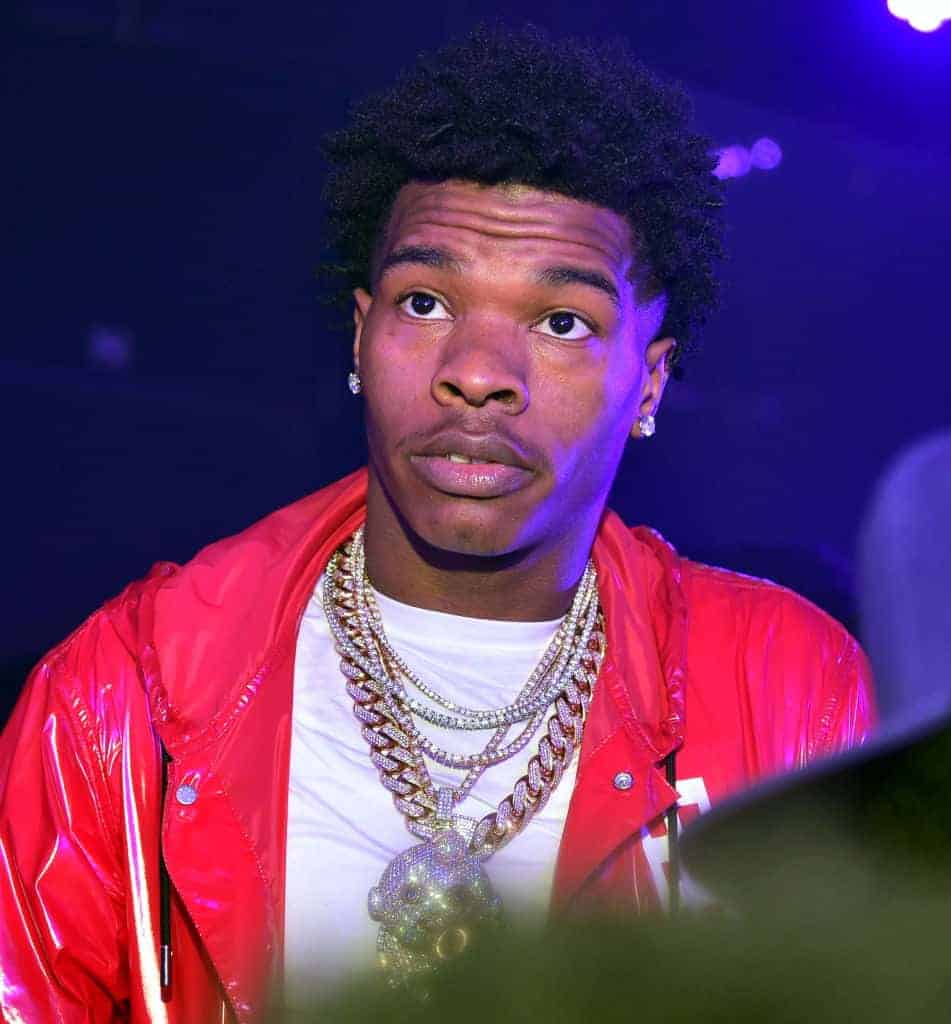 Lil Baby wearing a white tee and red jacket.