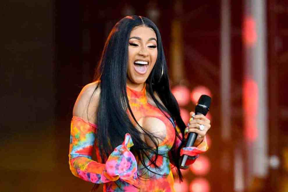 Cardi B wearing a multi-colored orange jumpsuit on stage