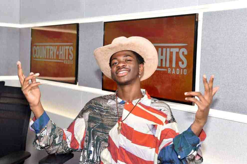 Lil Nas X sitting in a chair wearing red
