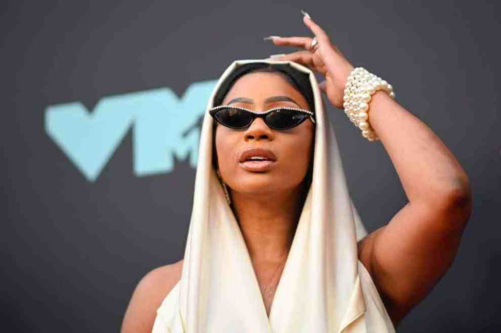 Tommie Lee wearing a cream hoodie and shades