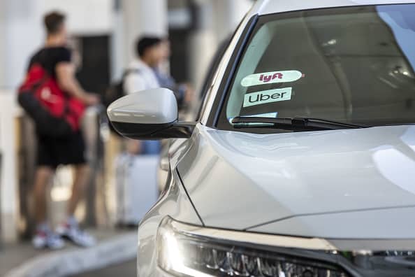 Lyft Inc. and Uber Technologies Inc. signage are displayed on the windshield of a vehicle at Los Angeles International Airport (LAX) in Los Angeles