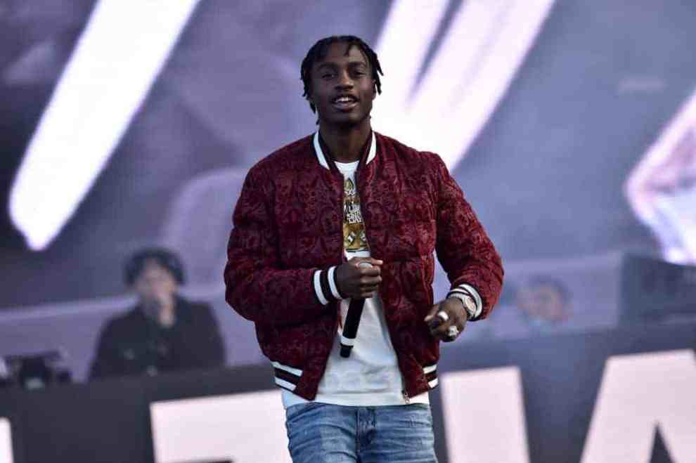 Lil Tjay wearing a red jacket on stage