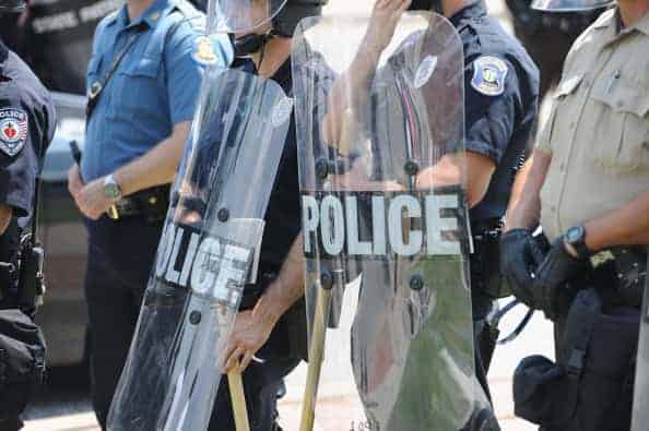 Police officers equipped in riot gear line up during a protest of the shooting death of 18-year-old Michael Brown outside Ferguson Police Department Headquarters August 11