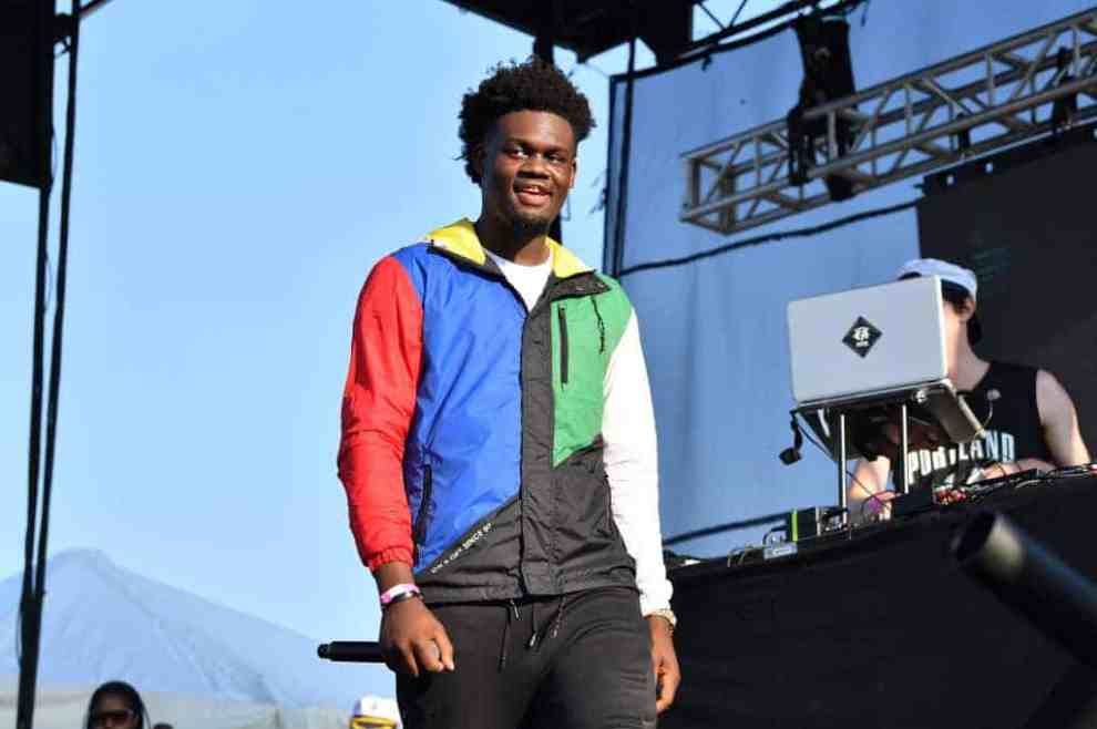 Ugly God wearing a colorful jacket performing on stage