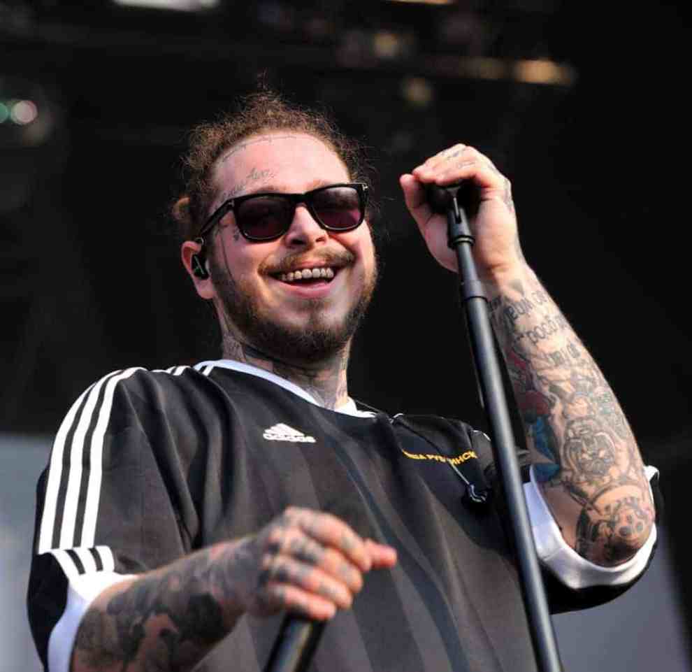 Post Malone wearing sunglasses and holding a microphone